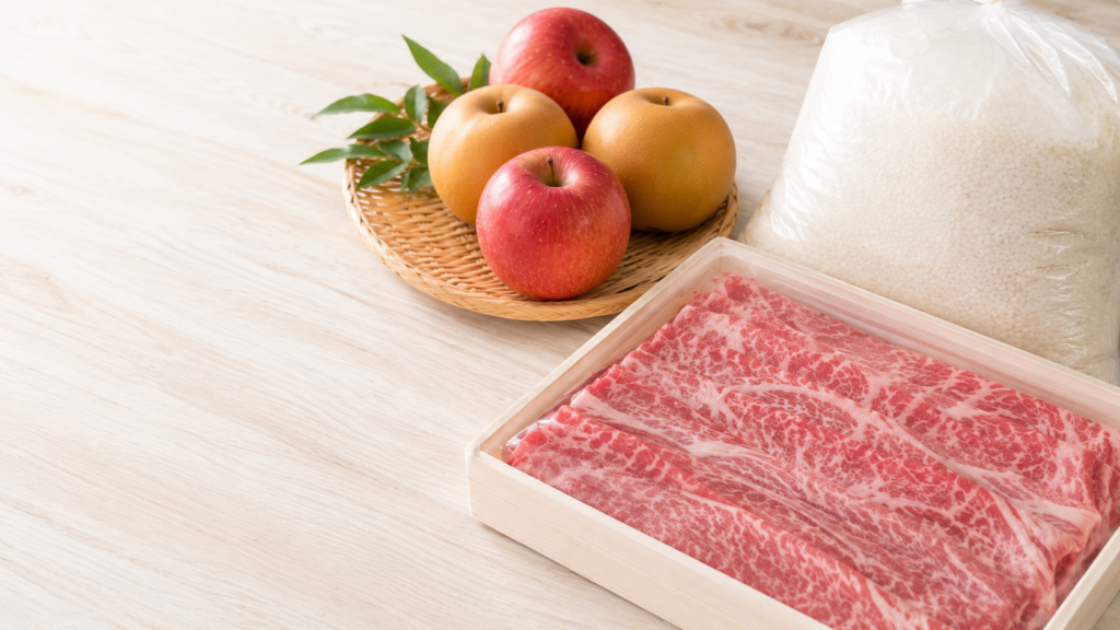 木のテーブルに並んだふるさと納税の返礼品のイメージ。りんご、梨、米、霜降り牛肉