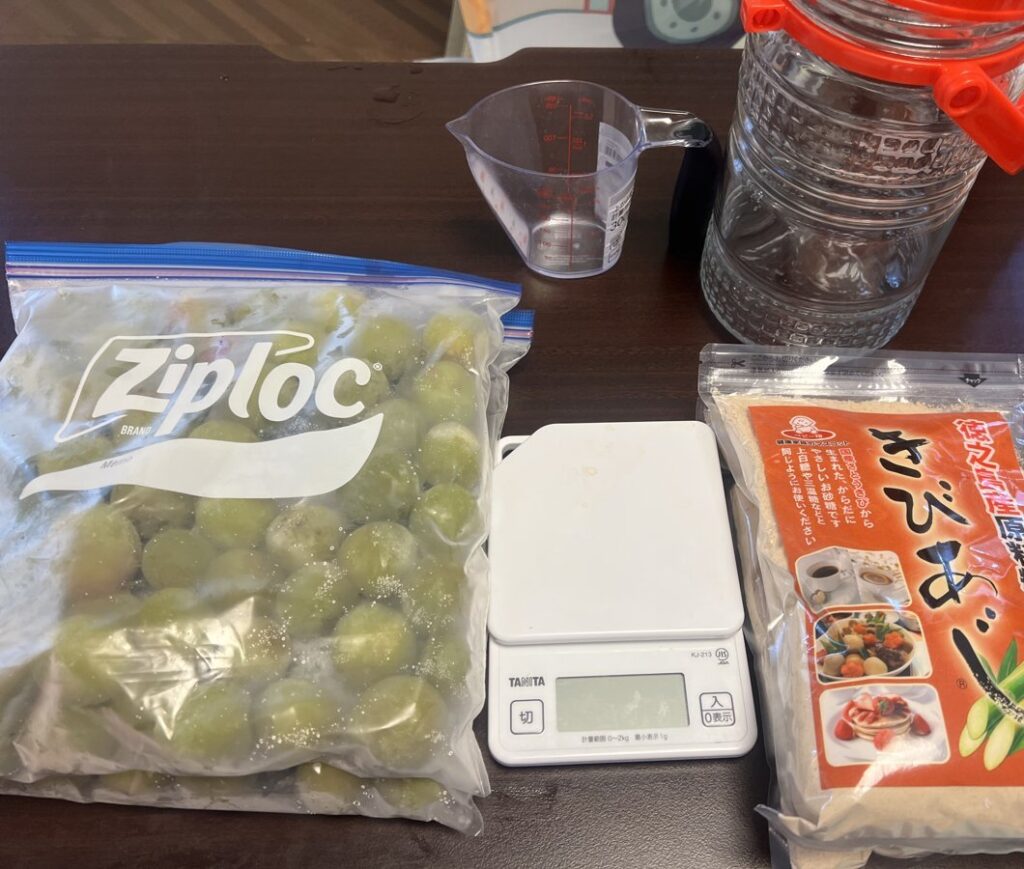 梅ジュースの材料。冷凍した青梅の入ったジップロック、キッチンスケール、きび砂糖、保存瓶